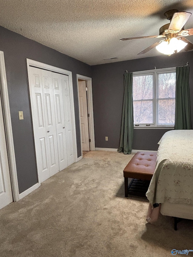 carpeted bedroom featuring a ceiling fan, visible vents, a textured ceiling, and baseboards