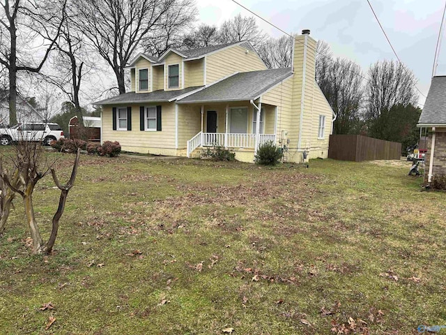 view of front facade featuring a front lawn, a chimney, fence, and a porch