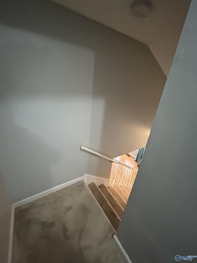 staircase with lofted ceiling, carpet, and baseboards