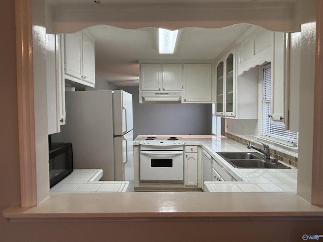 kitchen with glass insert cabinets, white appliances, white cabinetry, and a sink