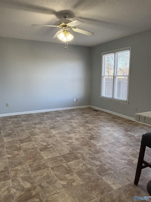 unfurnished room featuring a textured ceiling, a ceiling fan, and baseboards