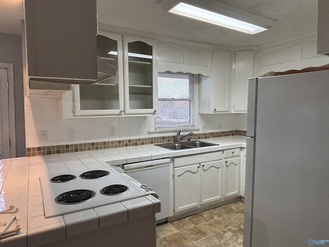 kitchen with tile countertops, tasteful backsplash, white cabinetry, a sink, and white appliances