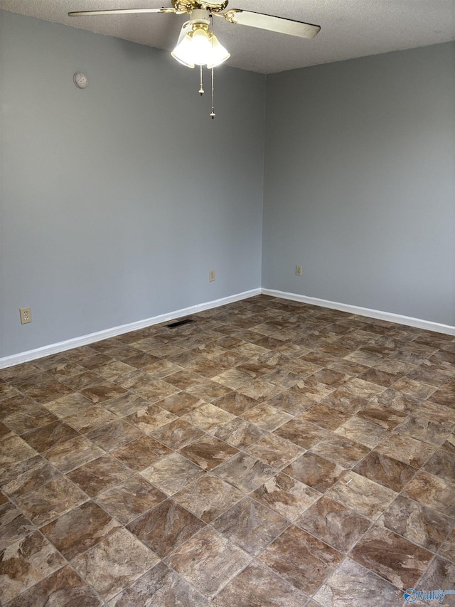 empty room with a ceiling fan, a textured ceiling, and baseboards