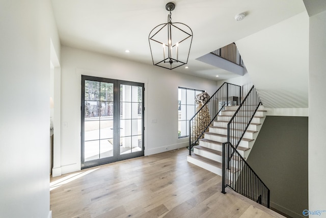 entrance foyer featuring french doors, light wood-type flooring, and an inviting chandelier