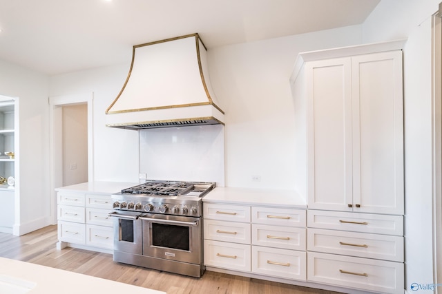 kitchen featuring premium range hood, white cabinetry, double oven range, and light wood-type flooring