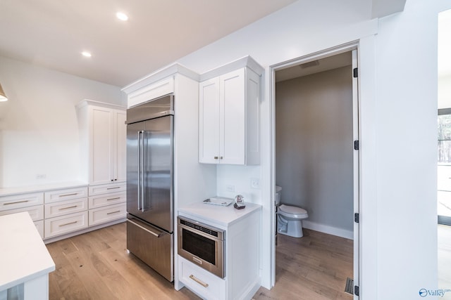 kitchen featuring white cabinetry, light hardwood / wood-style floors, and appliances with stainless steel finishes