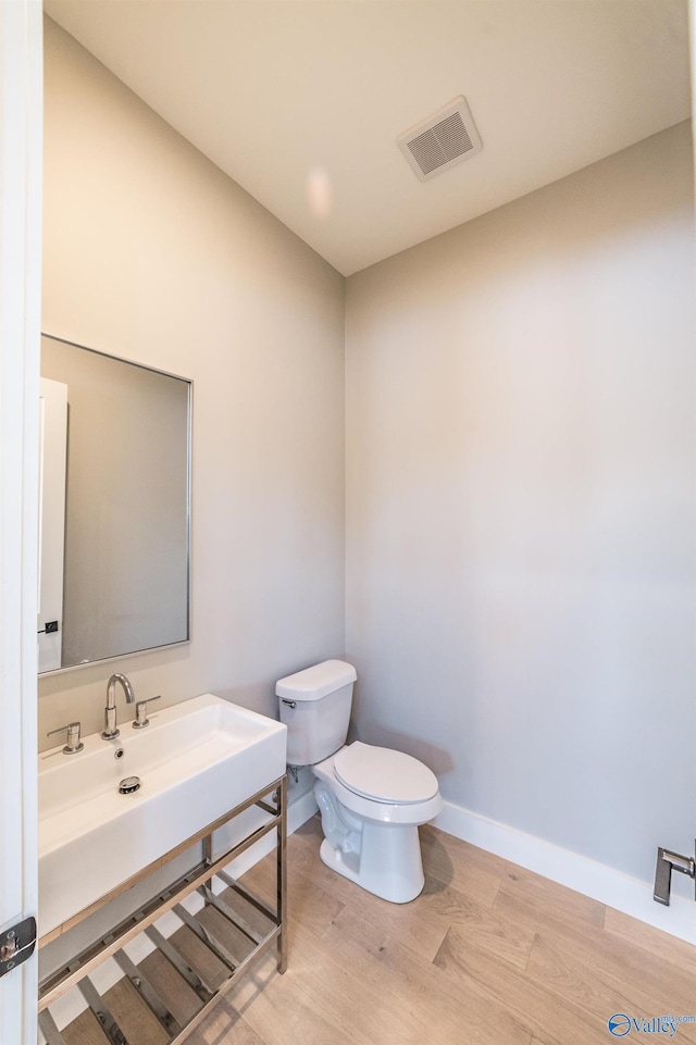 bathroom with toilet, wood-type flooring, and sink