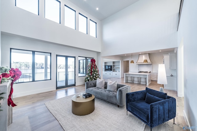 living room with light hardwood / wood-style floors, a high ceiling, and french doors