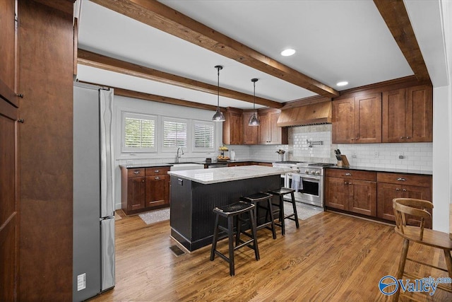 kitchen featuring decorative backsplash, a breakfast bar, light wood-type flooring, a sink, and appliances with stainless steel finishes