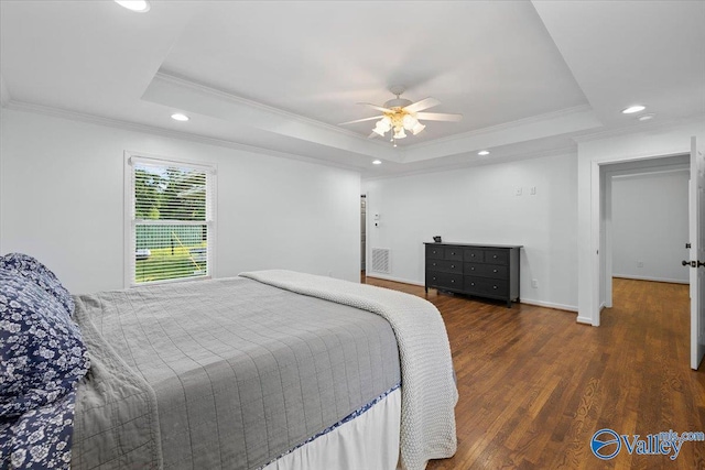 bedroom featuring recessed lighting, ornamental molding, wood finished floors, and a tray ceiling