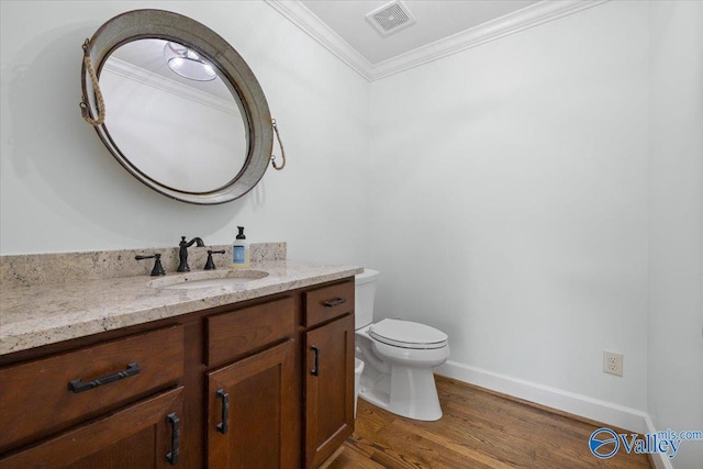 bathroom featuring crown molding, vanity, toilet, wood finished floors, and visible vents