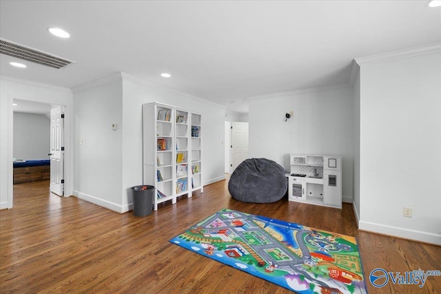 playroom featuring baseboards, visible vents, ornamental molding, and wood finished floors