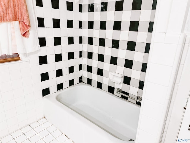 bathroom with tile patterned flooring, a bath, and tile walls