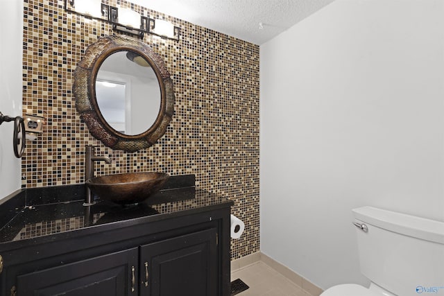bathroom featuring a textured ceiling, toilet, decorative backsplash, tile patterned floors, and vanity