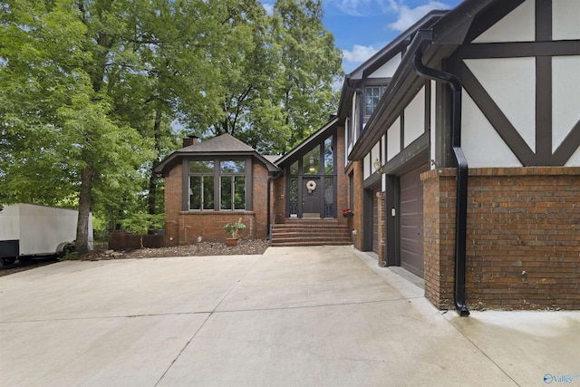 view of property exterior featuring concrete driveway, an attached garage, brick siding, and stucco siding