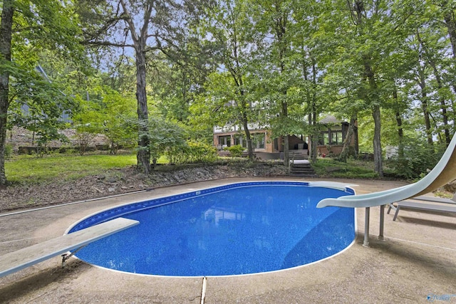 outdoor pool featuring a water slide and a diving board