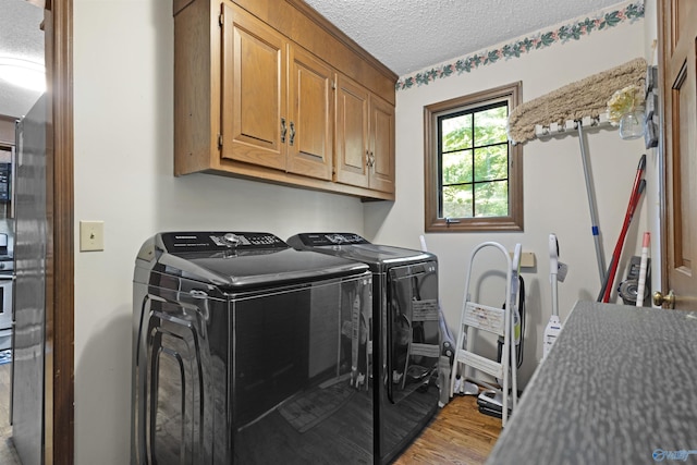 clothes washing area featuring cabinet space, independent washer and dryer, a textured ceiling, and wood finished floors