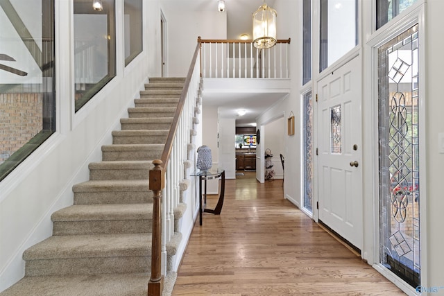 foyer entrance featuring wood finished floors, stairway, a high ceiling, and baseboards