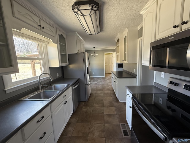 1903 Garner St, Scottsboro, AL 35769 - kitchen featuring a notable chandelier, glass insert cabinets, dark countertops, stainless steel appliances, and a sink