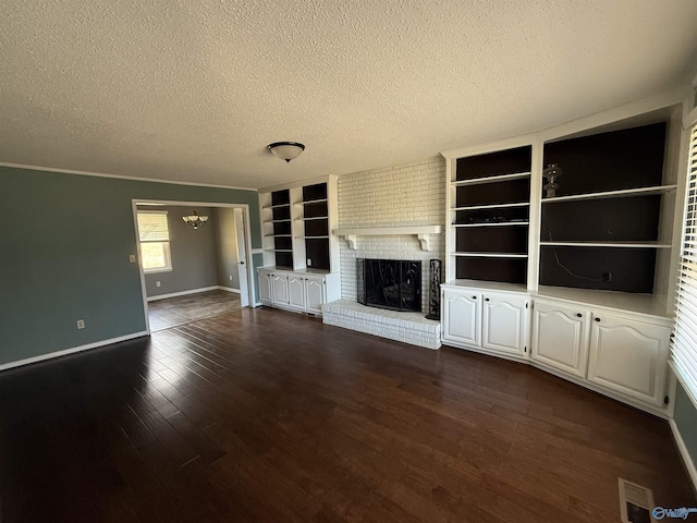 1903 Garner St, Scottsboro, AL 35769 - unfurnished living room with visible vents, a textured ceiling, a brick fireplace, and dark wood-style floors