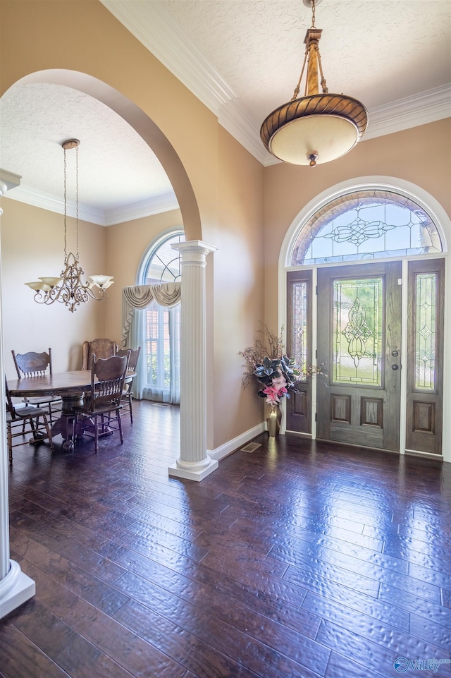 foyer entrance featuring hardwood / wood-style flooring, a textured ceiling, ornate columns, and ornamental molding