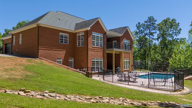 rear view of property with a balcony, a fenced in pool, a lawn, and a patio area