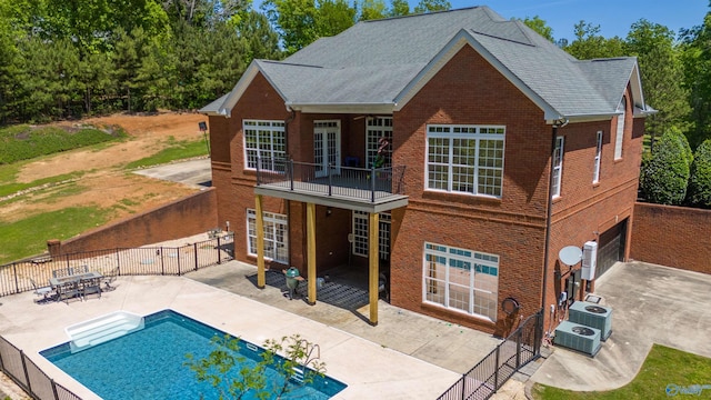 back of property featuring a balcony, french doors, a patio area, and a fenced in pool