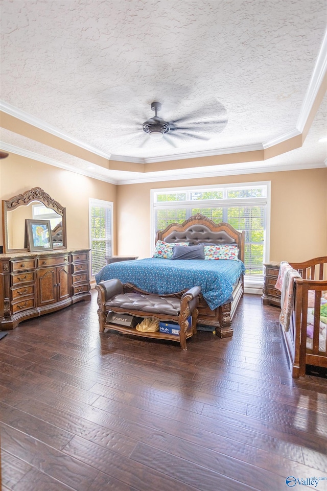 bedroom featuring ceiling fan, crown molding, dark hardwood / wood-style floors, and a tray ceiling