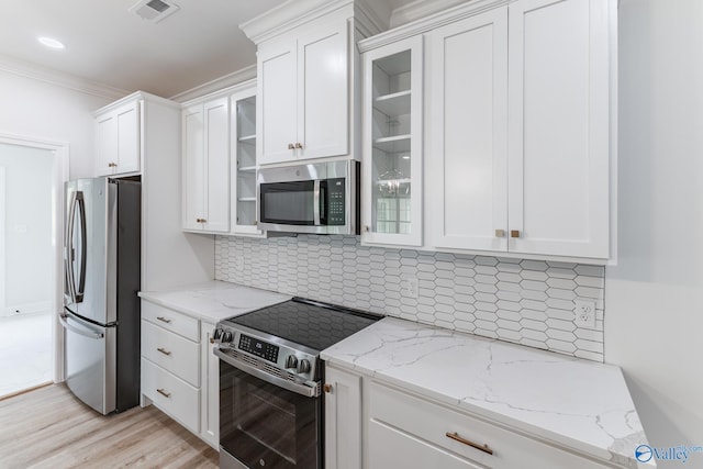 kitchen with appliances with stainless steel finishes, light stone counters, and white cabinets