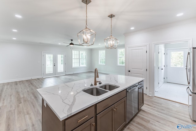 kitchen featuring appliances with stainless steel finishes, light hardwood / wood-style flooring, sink, and an island with sink