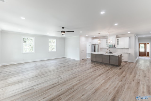 unfurnished living room with sink, ornamental molding, and a wealth of natural light