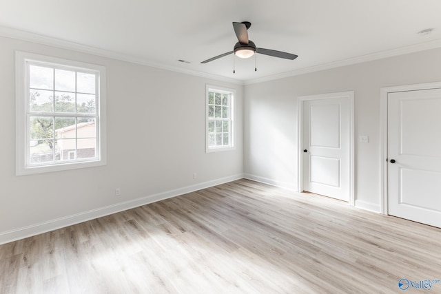 empty room with a wealth of natural light, ornamental molding, and light hardwood / wood-style flooring