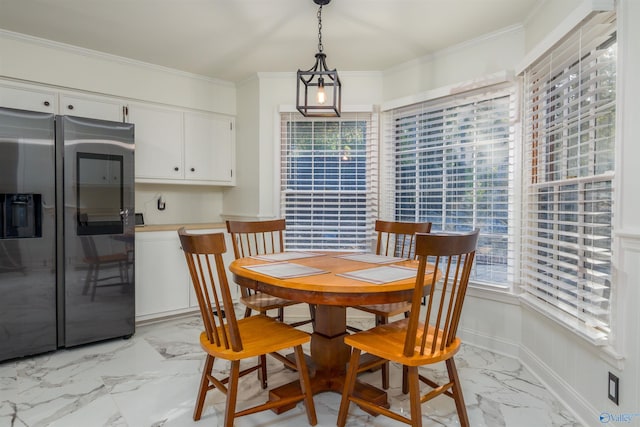 dining space with marble finish floor, crown molding, and baseboards