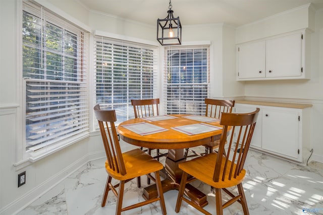 dining room with a wealth of natural light, marble finish floor, baseboards, and ornamental molding