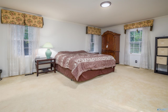 carpeted bedroom featuring visible vents, baseboards, and crown molding