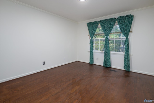 unfurnished room with visible vents, wood finished floors, baseboards, and ornamental molding