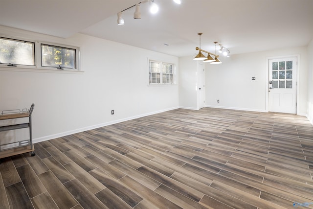 unfurnished room featuring track lighting, baseboards, and wood finished floors