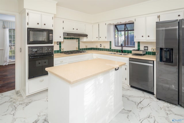 kitchen with marble finish floor, black appliances, ornamental molding, a sink, and under cabinet range hood