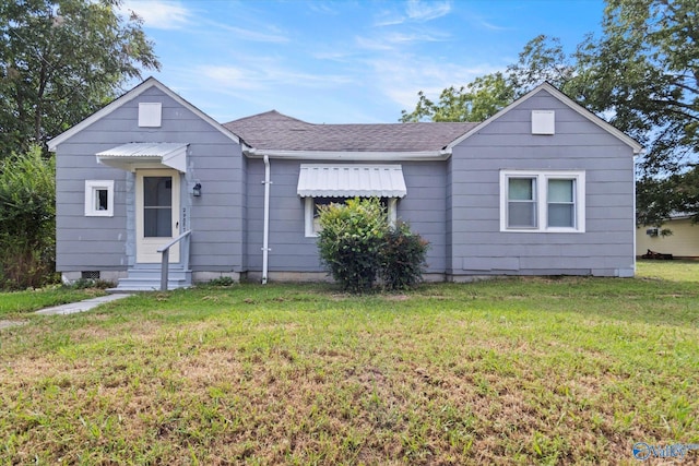 single story home featuring entry steps, roof with shingles, and a front lawn