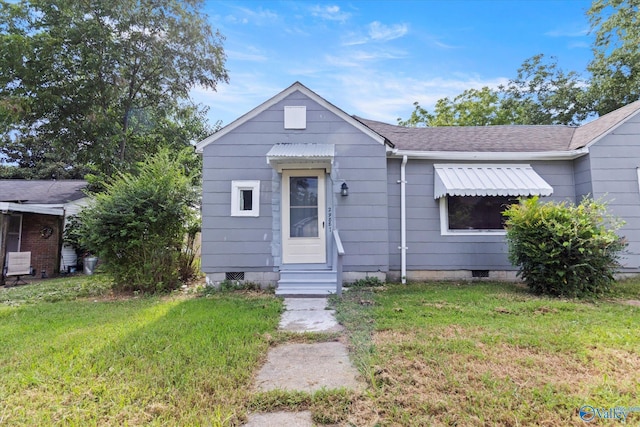 bungalow-style house featuring entry steps, a shingled roof, crawl space, and a front lawn