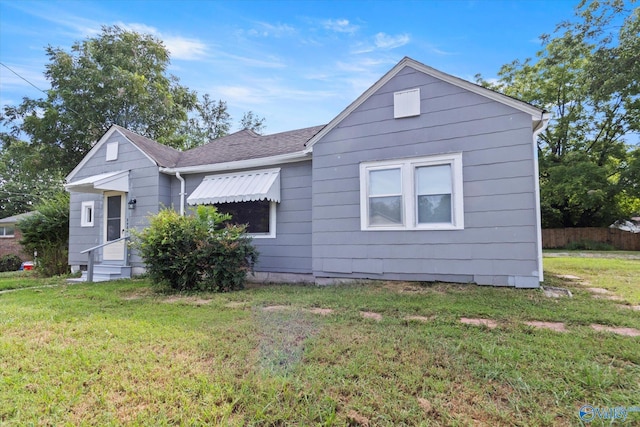 bungalow featuring a front lawn and roof with shingles