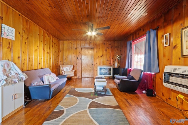 living area featuring wooden walls, wood-type flooring, wooden ceiling, and heating unit