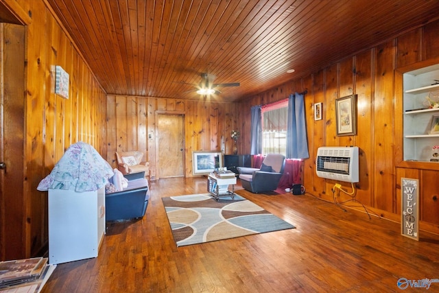 living room featuring wooden walls, wood-type flooring, wood ceiling, and heating unit