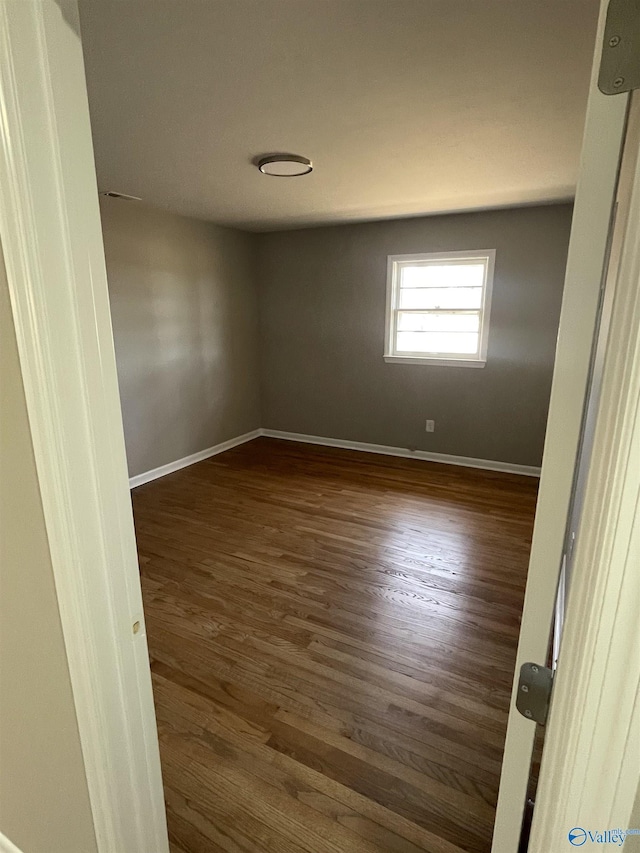 unfurnished room featuring baseboards and dark wood-style floors