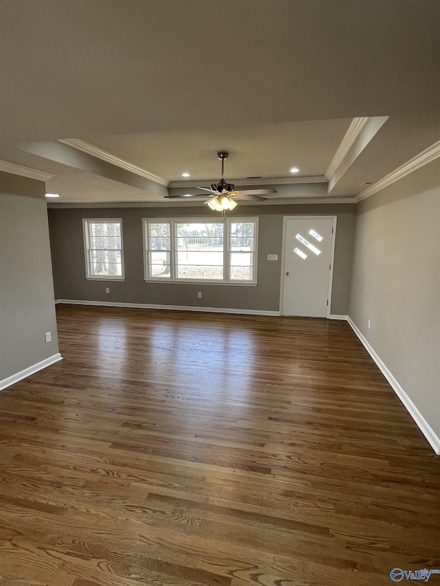 interior space featuring dark wood finished floors, crown molding, a raised ceiling, and a ceiling fan