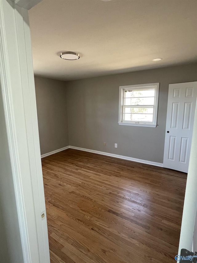 empty room featuring dark wood finished floors and baseboards