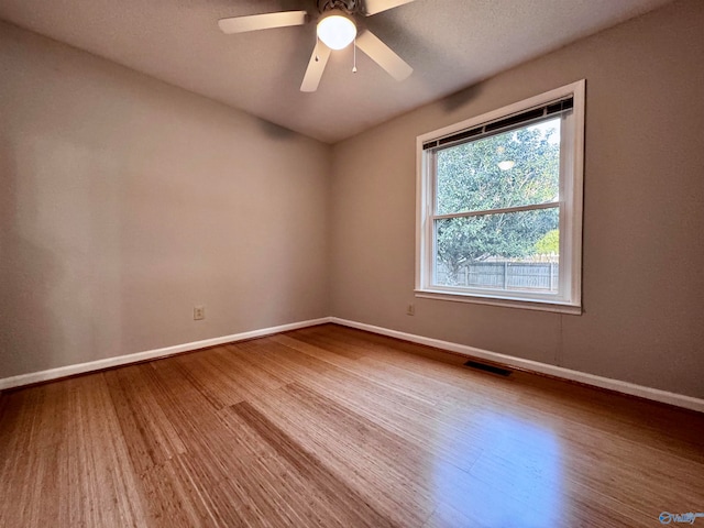 spare room featuring a ceiling fan, baseboards, visible vents, and wood finished floors