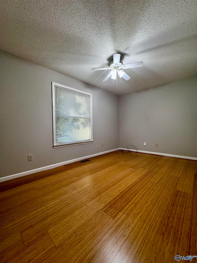 spare room with baseboards, ceiling fan, visible vents, and wood finished floors