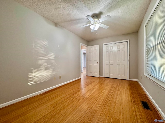 unfurnished bedroom with a closet, visible vents, a textured ceiling, light wood-type flooring, and baseboards