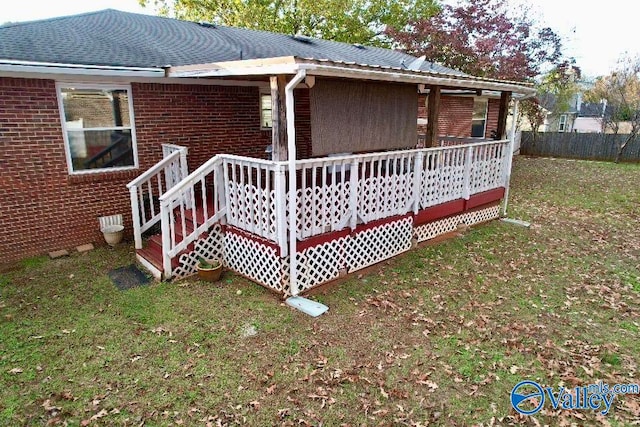 view of home's exterior featuring a yard, fence, brick siding, and a wooden deck